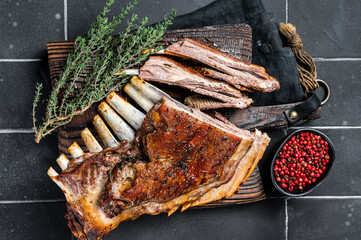 Grilled Rack of lamb ribs, mutton spareribs on wooden board. Black background. Top view
