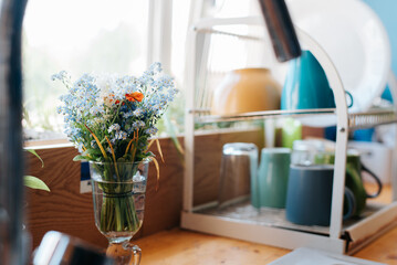 Close-up spring cute flowers in the kitchen on a sunny morning, selective focus on the bouquet with copy space
