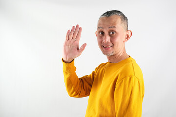 Portrait Asian Man with yellow long sleeve greetings and welcoming gestures, smiling face
