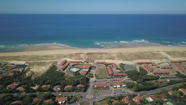 Aerial drone cinematic Hoosegor Capbreton France Bay of Biscay Quiksilver Pro waves central beach over city town street cars roadway world surf league sunny mid day slowly pan up forward movement