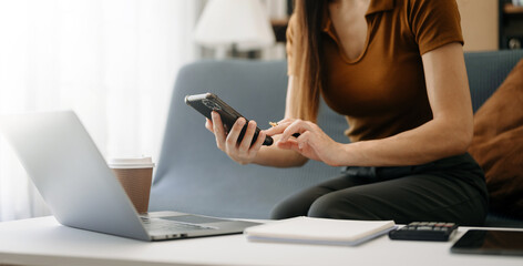 Naklejka premium Woman hand using smart phone, tablet payments and holding credit card online shopping, omni channel, digital tablet docking keyboard computer at office