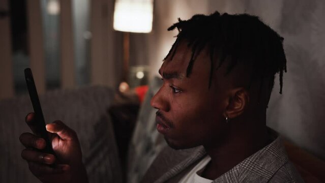 Young black male becomes shocked while looking at smart phone at home