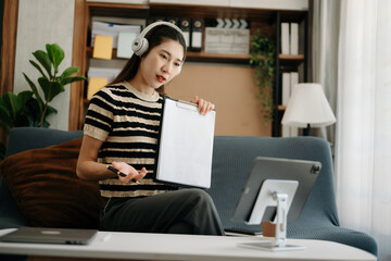Asian woman using the smartphone, laptop and tablet on the sofa at home