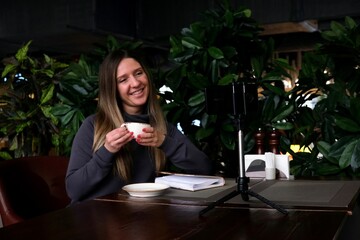 A woman is talking on a video chat in a cafe using a smartphone. communication, online communication, emotions and gestures.