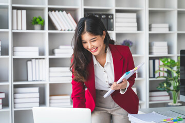 Asian happy businesswoman hold paper documents work stand at workplace. Attractive female employee office worker smile.