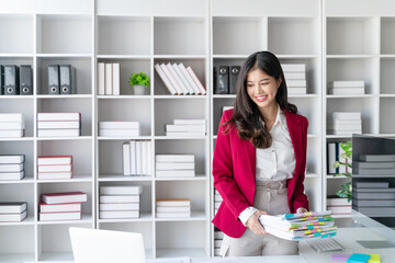 Fototapeta na wymiar Asian happy beautiful businesswoman hold paper documents work stand at workplace. Attractive female employee office worker smile.