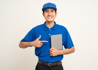 Asian man in blue uniform standing holding digital tablet computer on isolated white background. Male service worker with cell phone. Delivery courier shipping service