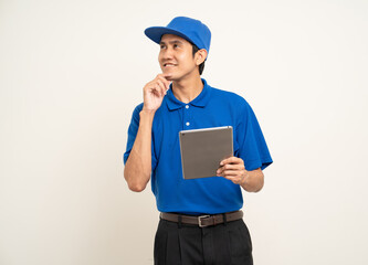 Asian man in blue uniform standing holding digital tablet computer on isolated white background. Male service worker with cell phone. Delivery courier shipping service