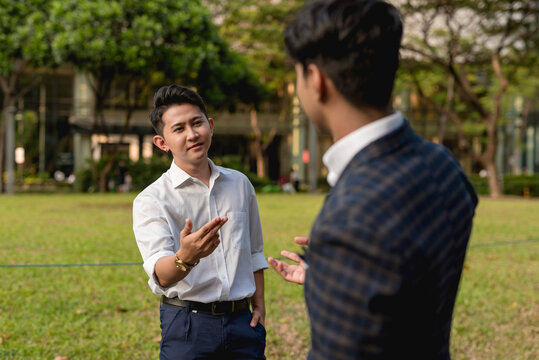 A young asian man has a casual conversation with an old friend after a chance encounter outside the office.