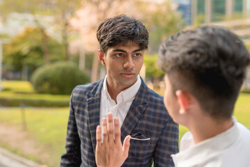 A young indian man bullies and physically threatens his fearful colleague while cornering him at...