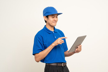 Fototapeta premium Asian man in blue uniform standing holding digital tablet computer on isolated white background. Male service worker with cell phone. Delivery courier shipping service
