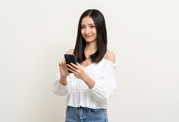 Naklejka premium Pretty young asian woman using smartphone standing on isolated white background. Excited Beautiful young asian shopping online payment with mobile phone. Playing game on smartphone