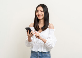 Pretty young asian woman using smartphone standing on isolated white background. Excited Beautiful young asian shopping online payment with mobile phone. Playing game on smartphone