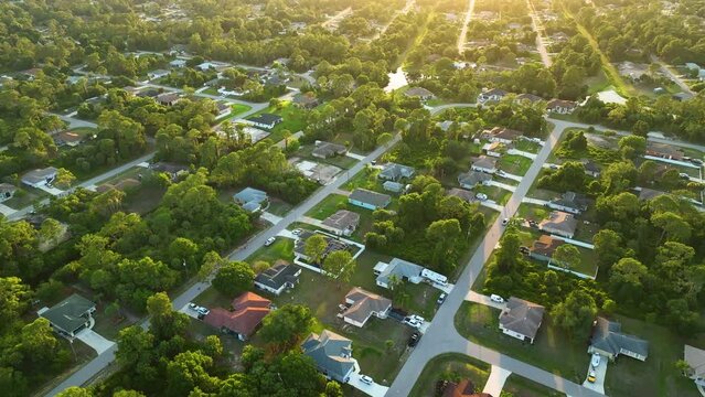 Aerial landscape view of suburban private houses between green palm trees in Florida quiet rural area at sunset