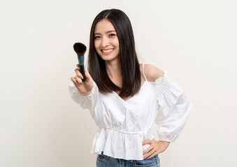 Beautiful smiling happy young asian woman holding brush make up. Charming female lady standing pose on isolated white background. Asian cute people confident with cosmetic