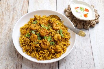 Prawns Biryani or shrimp Pulao. also called jheenga pilaf or jhinga biryani in India. known as Kolambi bhat in Marathi. Garnished with mint leaves, and coriander along with yogurt Raita. Copy space