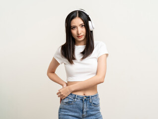 Cheerful asian female teenager listen to the music with white headphone dancing on isolated white...