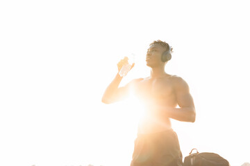 Young athlete man listening music while resting after training. Handsome African man training outside