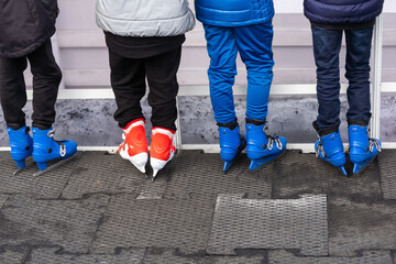 Close-up of family of three wearing skates standing on skating rink they going to skate.