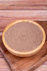 Allspice powder spice on wooden background. Powdered dried allspice in wooden bowl. Pimento spice, Jamaican pepper and shavings