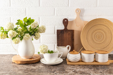 Beautiful front view of various kitchen utensils and cutting boards on a dark marble countertop against a white brick wall. kitchen background.