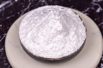 Powdered sugar on dark background. Powdered or icing sugar in bowl