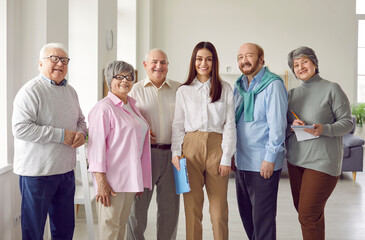 Group portrait of happy old people and young business coach. Elderly men and women with pencils and...