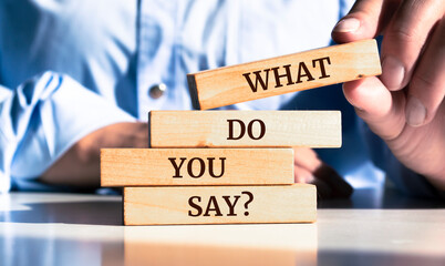 Close up on businessman holding a wooden block with a "What Do You Say?" message