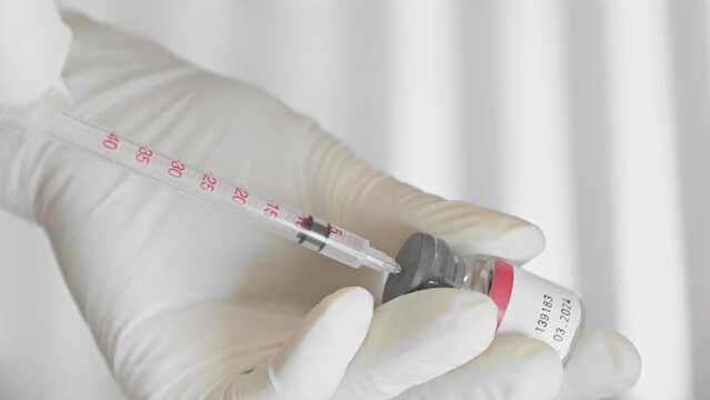 In the beauty salon, a close-up of the hand of beautician professional who will prepare for botulinum therapy for rejuvenation and facial skin care. Picks up with a syringe drug butulin for injection.