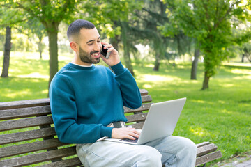 Young Caucasian man multitasking outdoors with laptop and phone