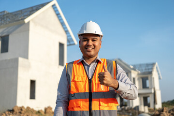 Confident engineer handsome man at modern home building construction. Architect with white safety helmet at site. Real Estate building under construction. Foreman senior worker project designer
