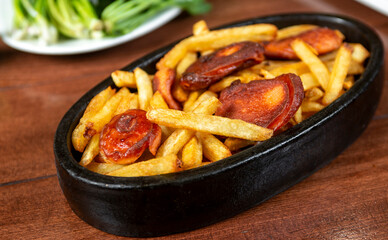 Frying pan with pieces fried sausage and potato