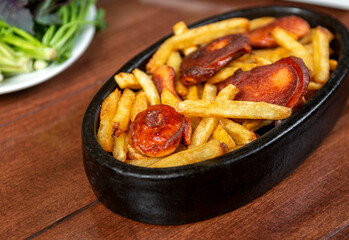 Frying pan with pieces fried sausage and potato