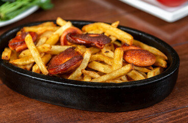 Frying pan with pieces fried sausage and potato