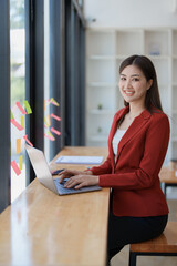 Portrait of a woman business owner showing a happy smiling face as he has successfully invested her business using computers and financial budget documents at work