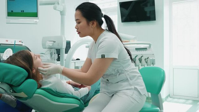 Concentrated asian dentist woman examining patient oral cavity in hospital. Doctor appointment
