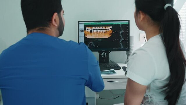 Serious indian and asian dentists discuss panoramic picture of patients oral cavity and treatment