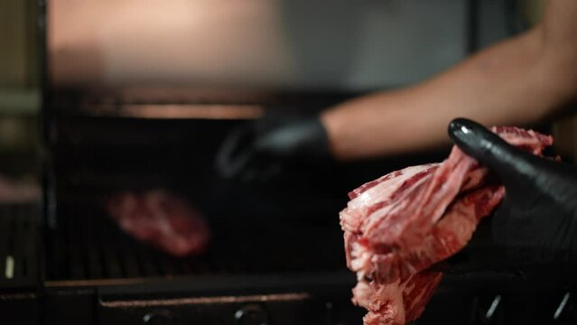 Close up of chef's hands laying beef steak on grill. Super slow motion. barbecue or BBQ.