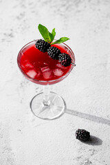 Fototapeta na wymiar Blackberry Cocktail Blackberry Martini with fresh berries, ice and mint. Refreshing alcoholic drink with blackberry and ice on a stone grey background. Cocktail drink photography