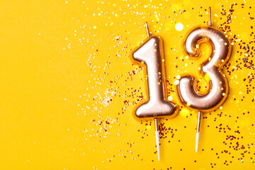 Gold candles in the form of number thirteen on yellow background with confetti. 13 years...