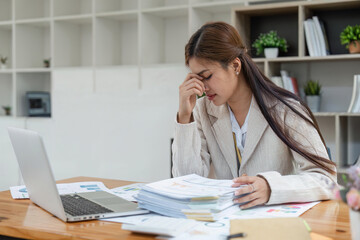 Business women are stressed while working on laptop and pile of documents, Tired businesswoman with headache at office, feeling sick at work