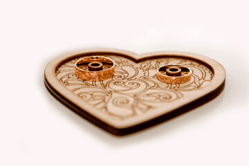 Wedding gold rings on a saucer with a heart. The accessory is a symbol of fidelity for the fingers of the newlyweds.