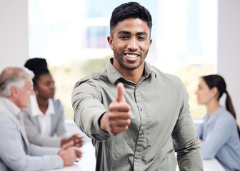 Portrait, smile and a business man thumbs up in the boardroom with his team planning in the background. Leadership, workshop and motivation with a happy young male employee standing in the office