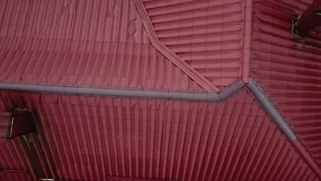 Aerial top view of house metal roof of red color. Drone footage.