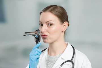 Female gynecologist makes funny gestures with a speculum to take away the fear