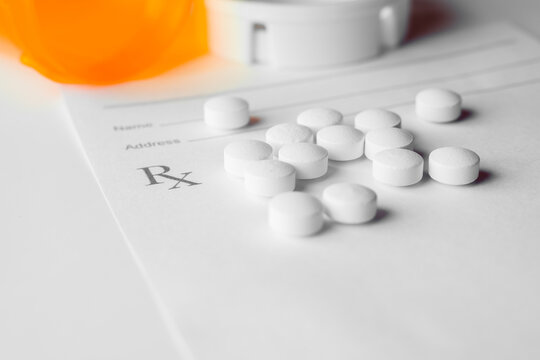 white prescription pills laying on rx pad on white background