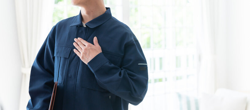 胸に手を添える作業着を着たスタッフ（信用・信頼・安心）