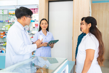 Obraz premium Medical pharmacy and healthcare providers concept. Professional Asian man and woman pharmacist recommend and selling medical product, medicine, drugs and supplements to patient customer in drugstore.