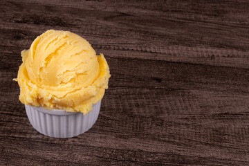 Yellow ice cream served in a white pot. Food aligned on the left with empty space for texts on the right.