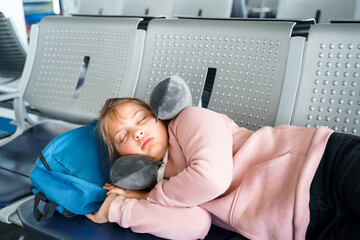 Kid, teen tired girl sleeping, waiting in airport passenger terminal departure hall with backpack....